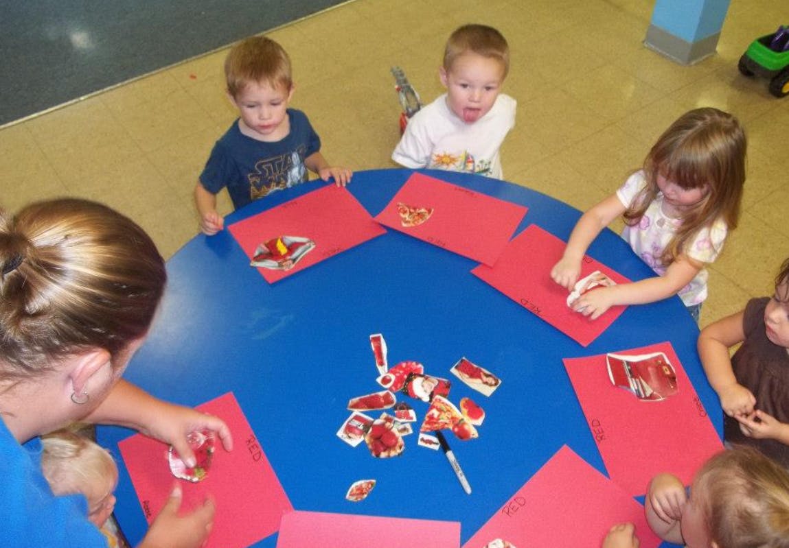Adult and children doing crafts at a blue table