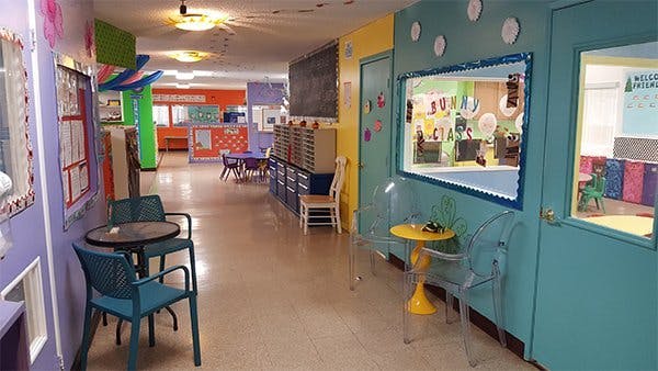 Hallway with tables and chairs, windows looking into classrooms