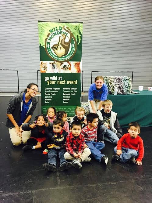 Two adults and several children sitting in front of a banner