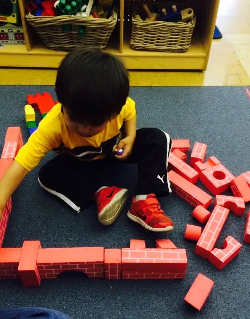 Child playing with red building blocks on the floor