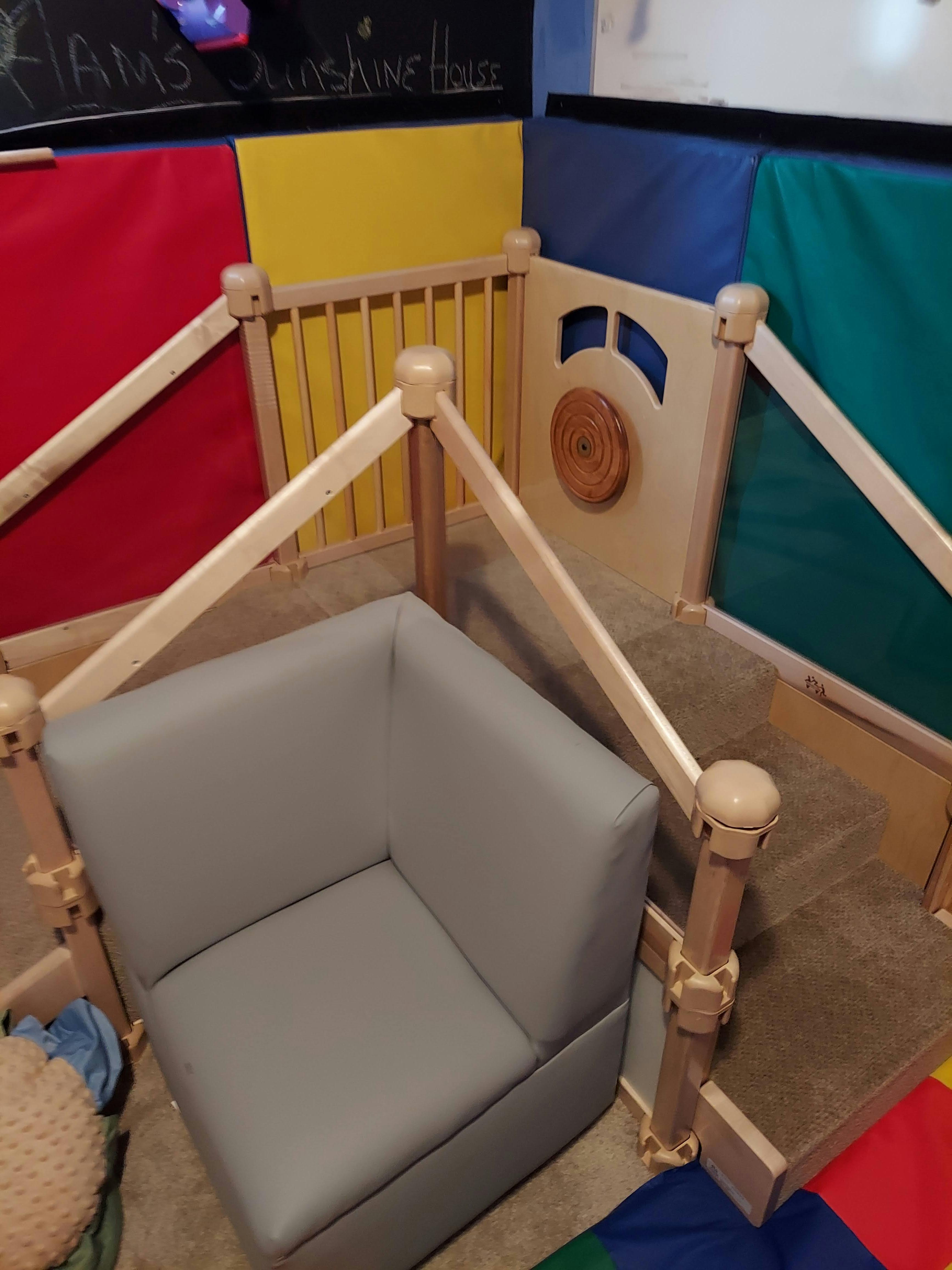 Corner of a gray modular sofa inside a wooden playpen