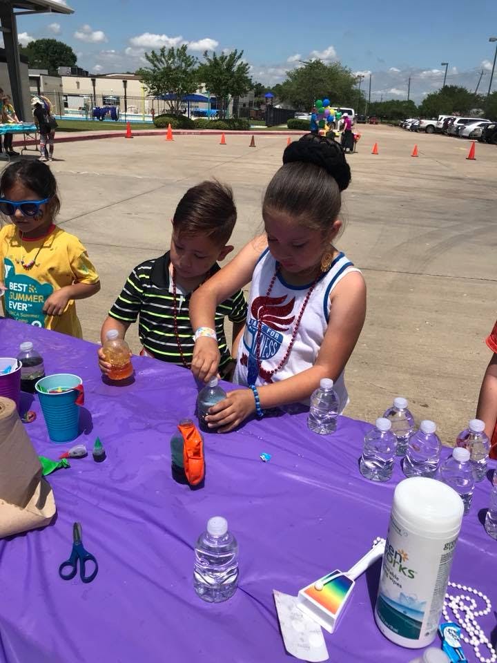 Three children at a table with bottles and craft supplies
