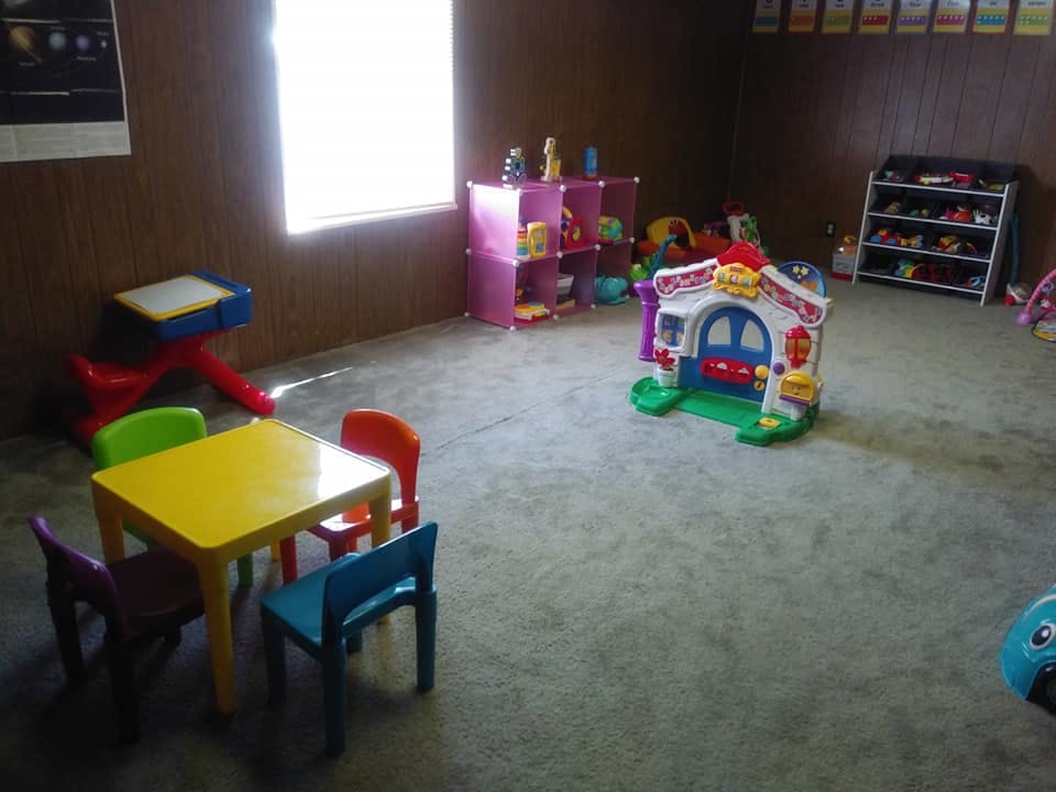 Playroom with small table and chairs, toy house, and shelves with shelves of toys