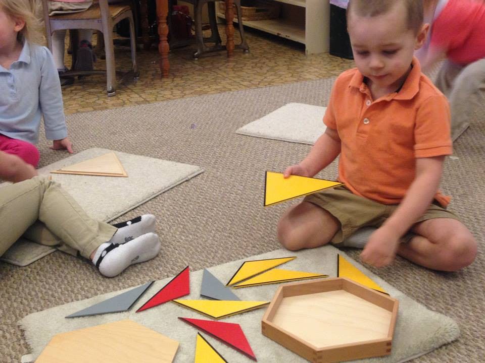 Child playing with colorful geometric shapes on the floor