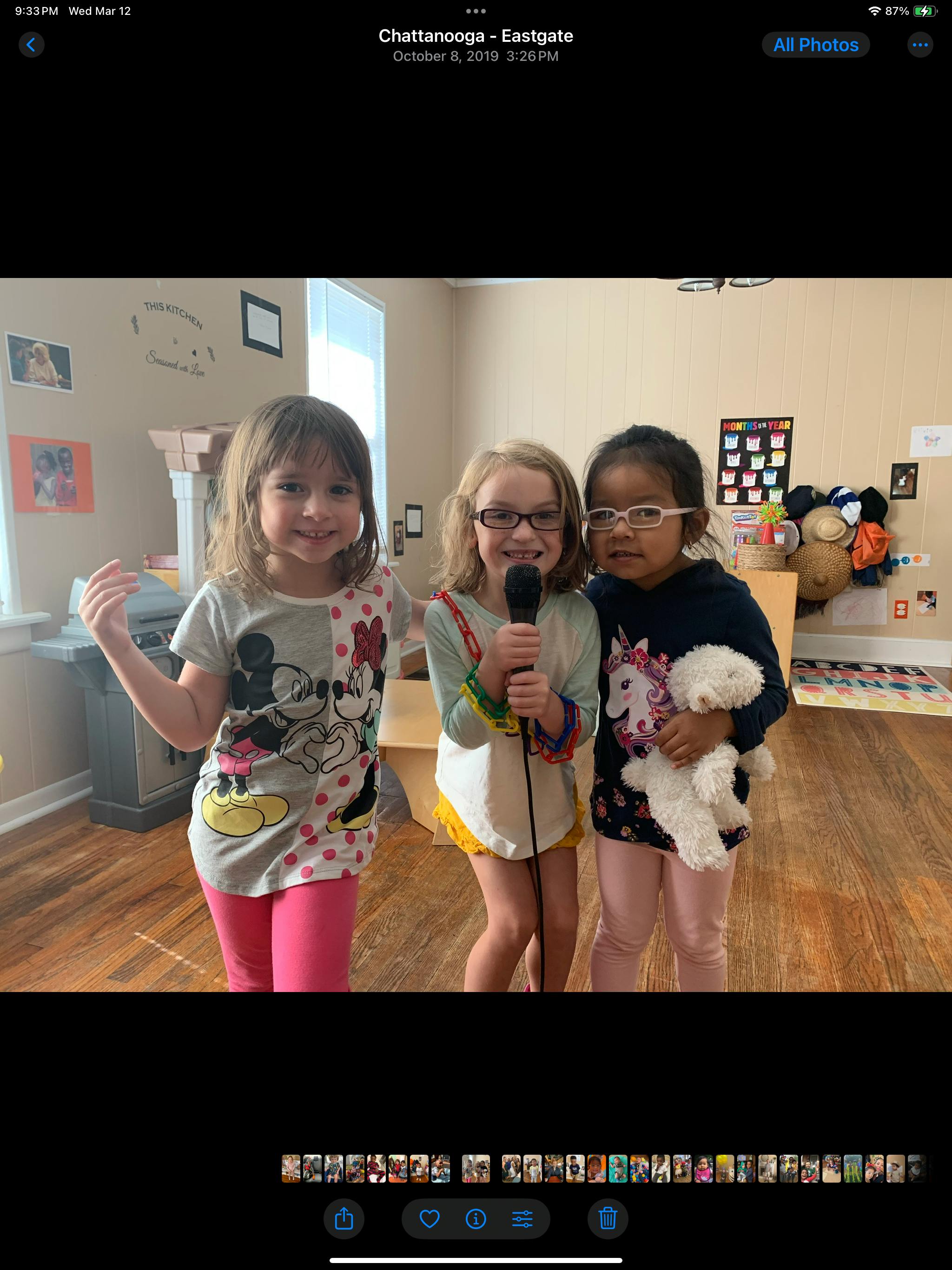 Three children standing together, one holding a microphone, another holding a stuffed animal