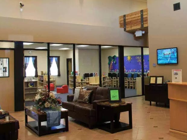Lobby area with couches and a coffee table, classroom visible through glass partition