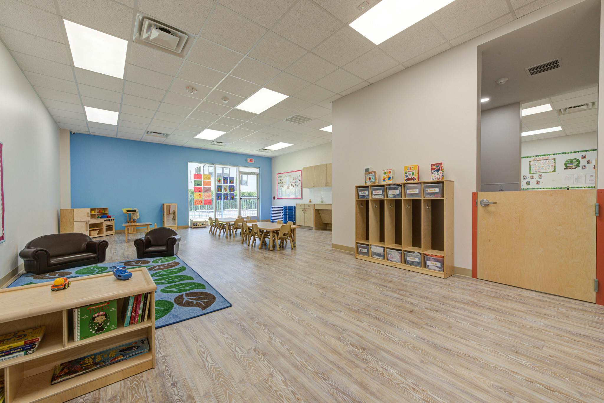 Empty children's classroom with small tables and chairs, play area