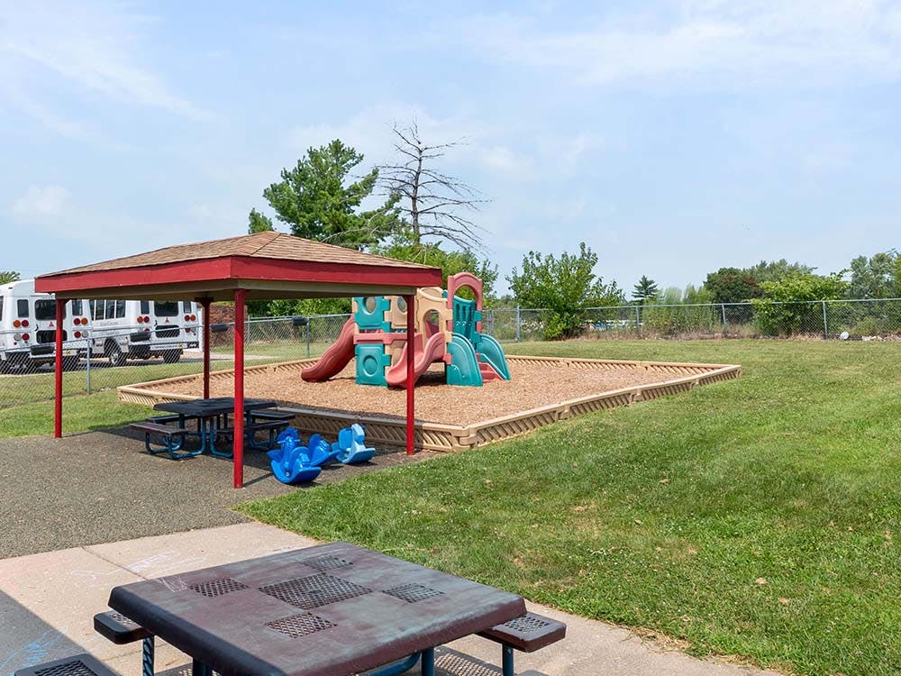 Outdoor playground with slide, swings, and covered picnic tables