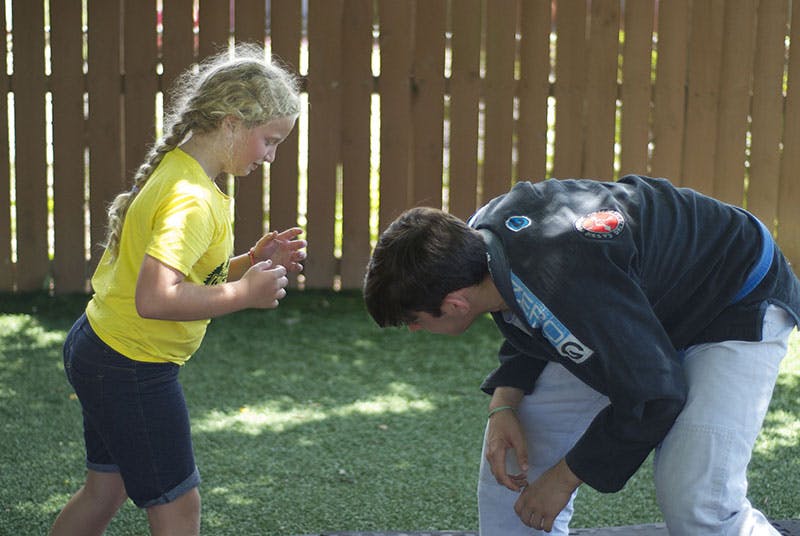 Child in yellow shirt facing person bending over