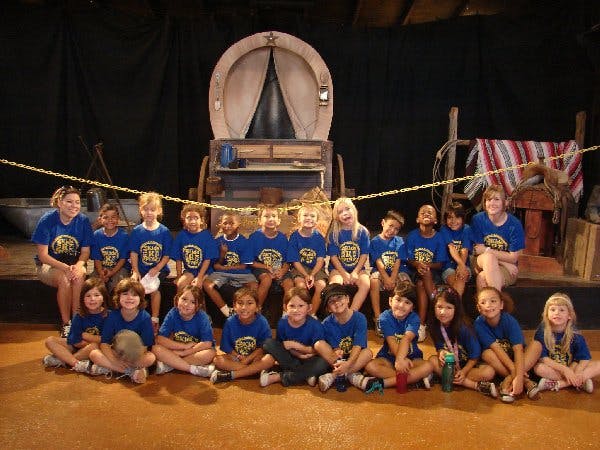 Group of adults and children in blue shirts sitting on the floor