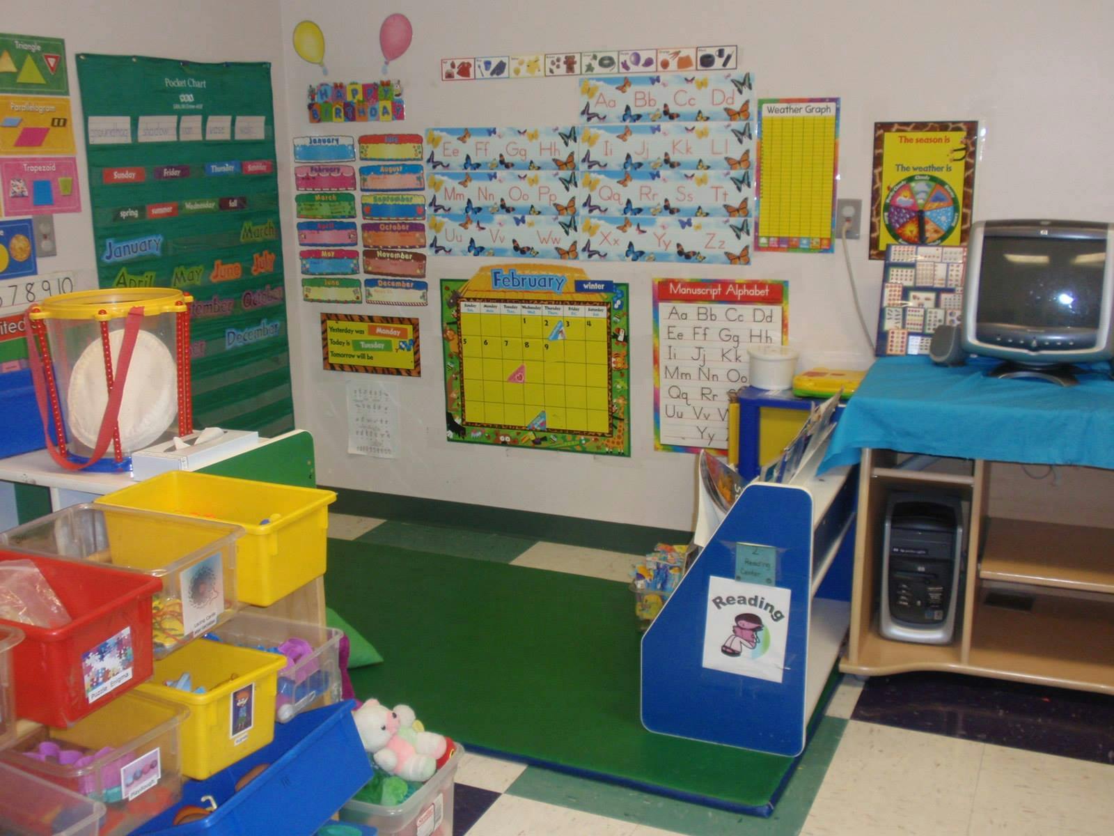 Classroom with colorful charts on walls, storage bins, and a computer