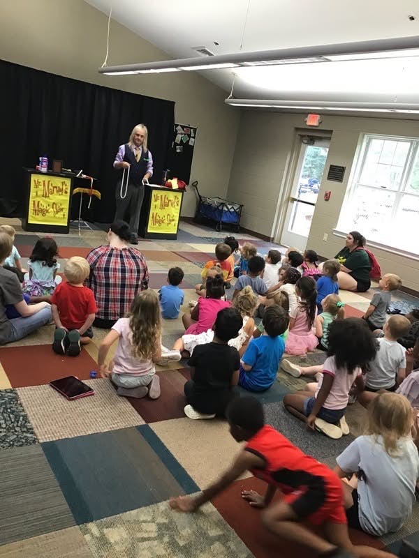 Magician performing a show for a group of children sitting on the floor