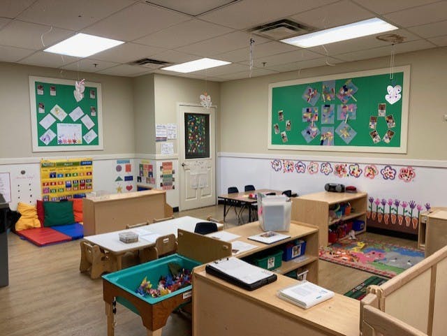 Empty classroom with bulletin boards, small tables, and colorful rugs