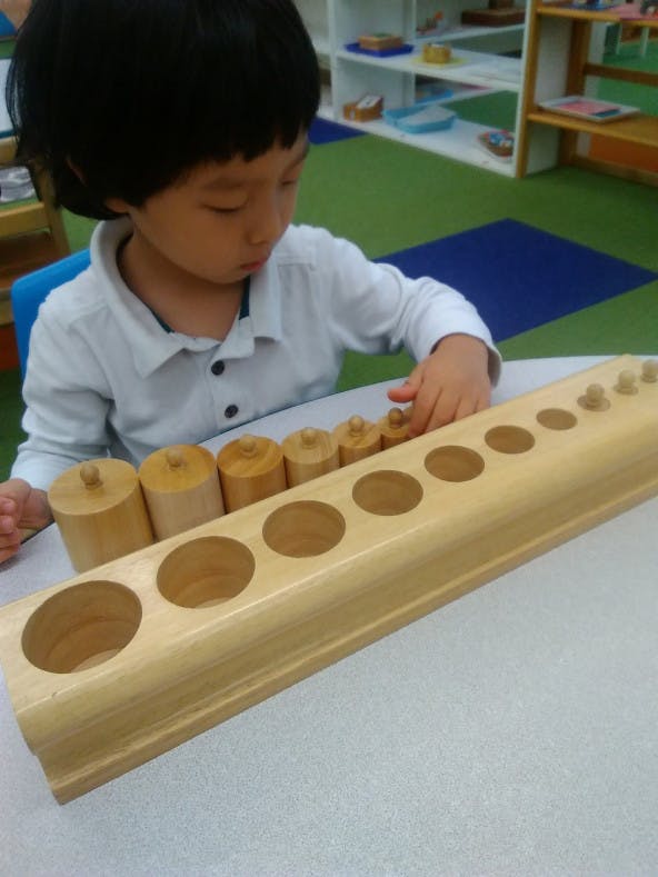 Child playing with a wooden cylinder block puzzle