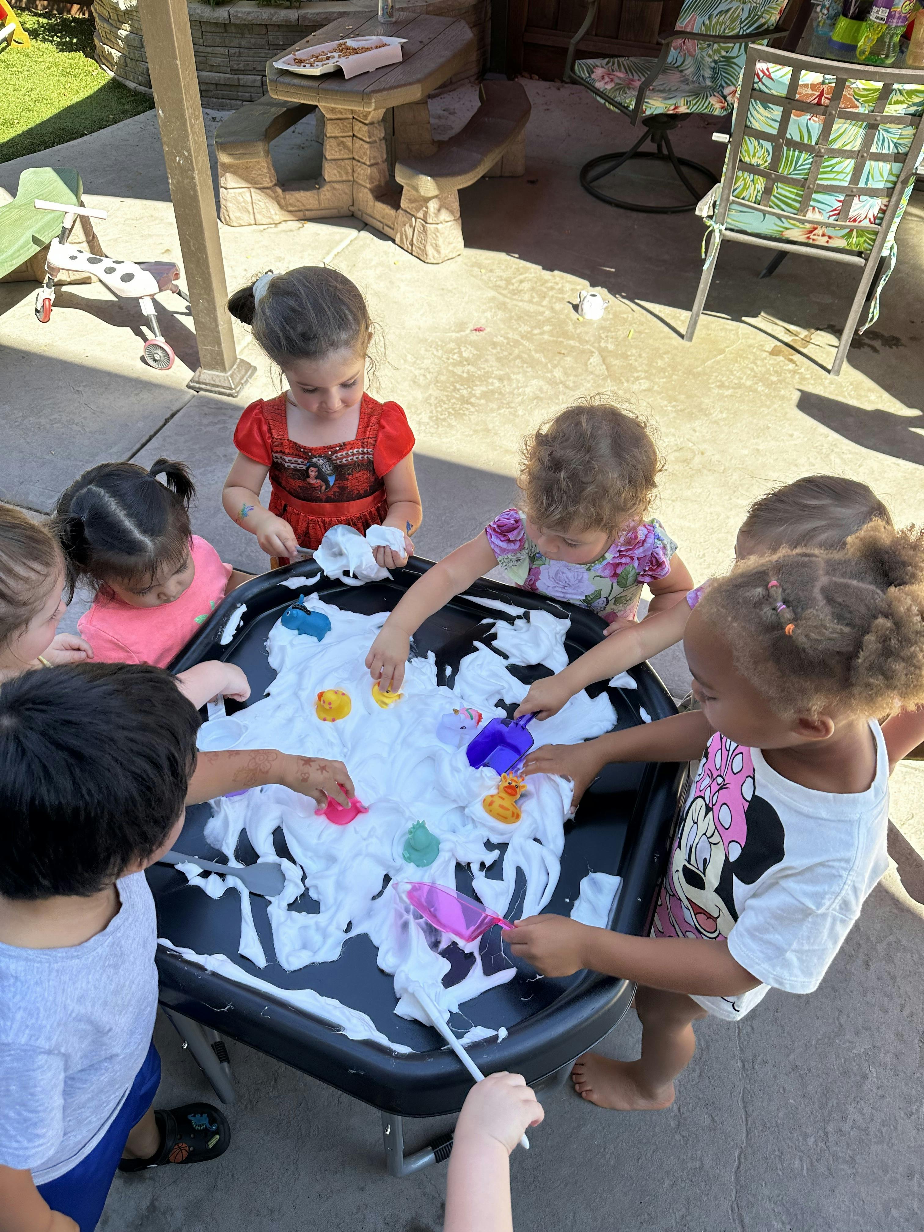 Children playing with shaving cream and toys in a sensory bin