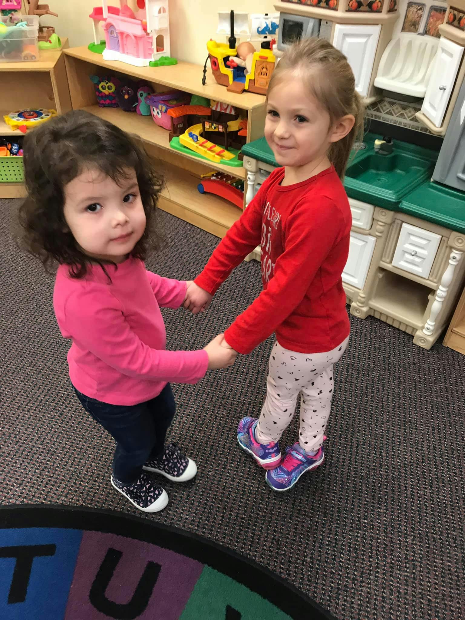 Two children holding hands in a classroom