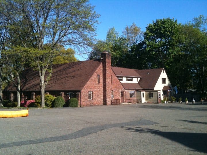 Brick building with a brown roof and a large paved area in front