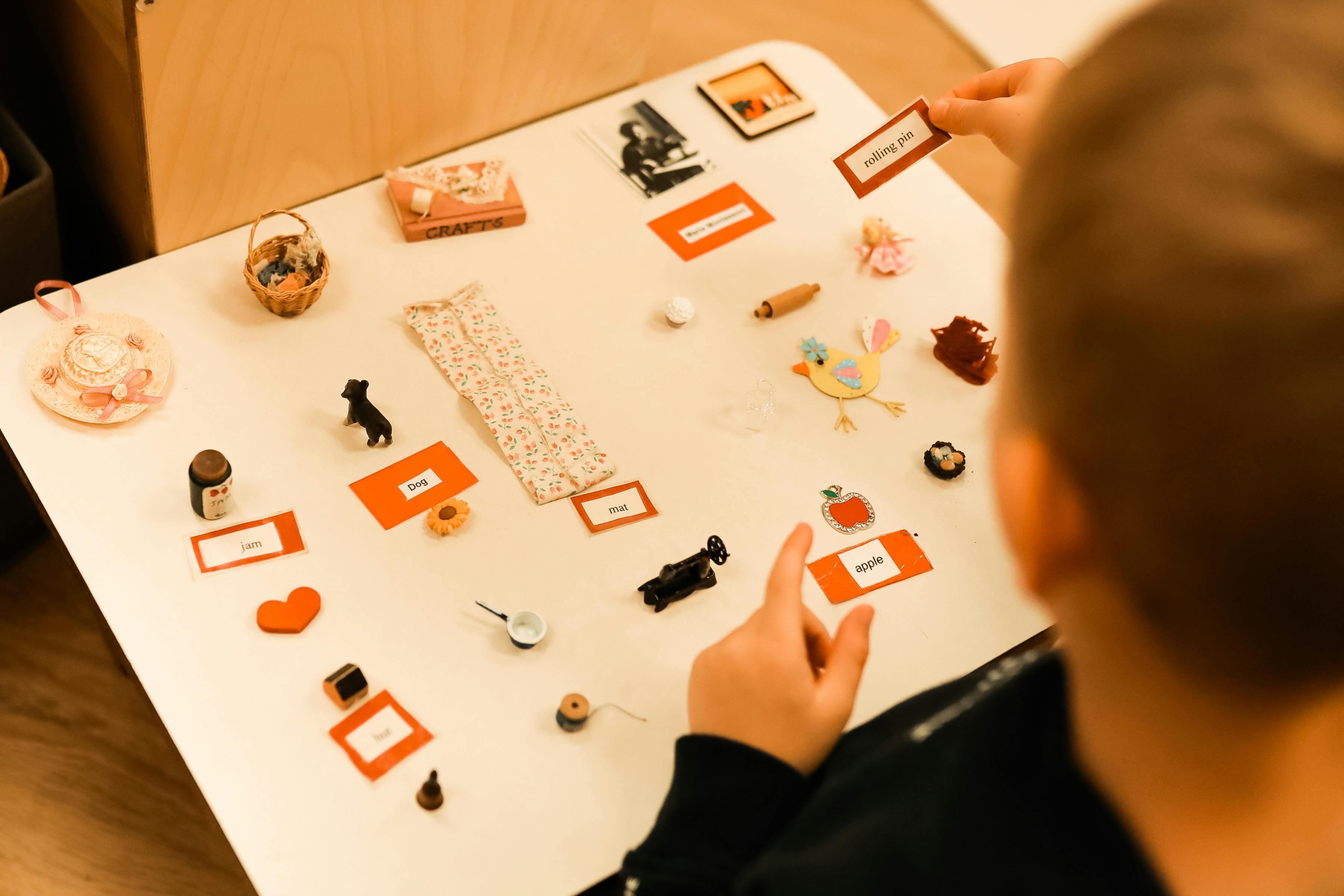 Child playing with small objects and word cards on a table