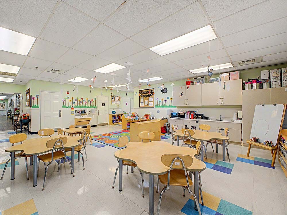 Empty classroom with small tables, chairs, and colorful decorations