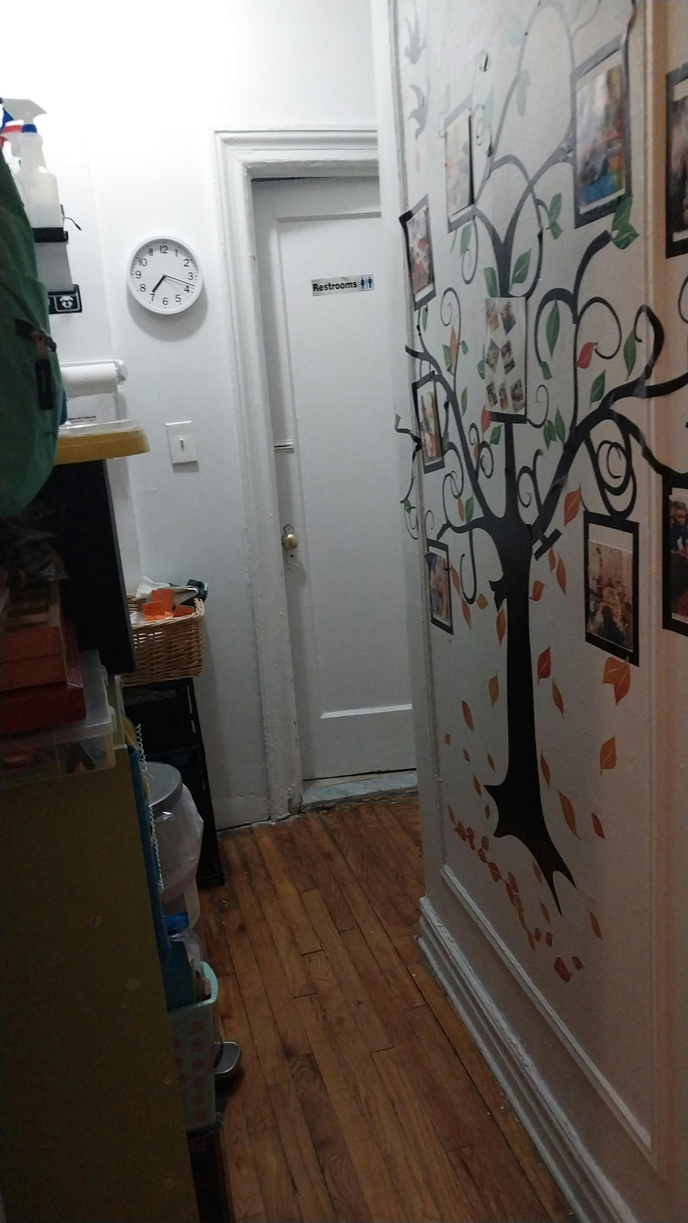 Hallway with a tree decal on the wall and a door with a "Restroom" sign
