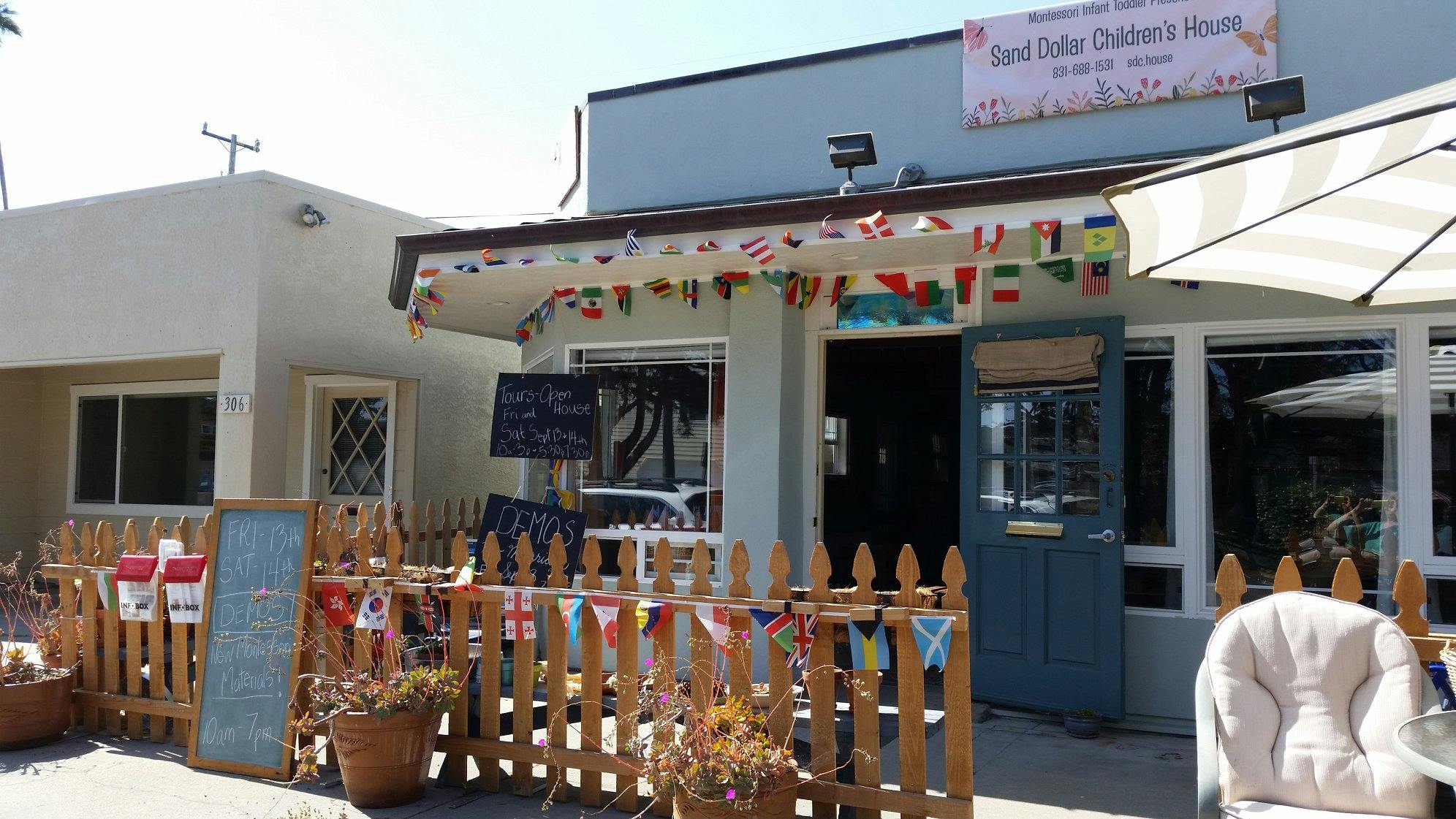 Building exterior with a blue door and a wooden fence decorated with flags