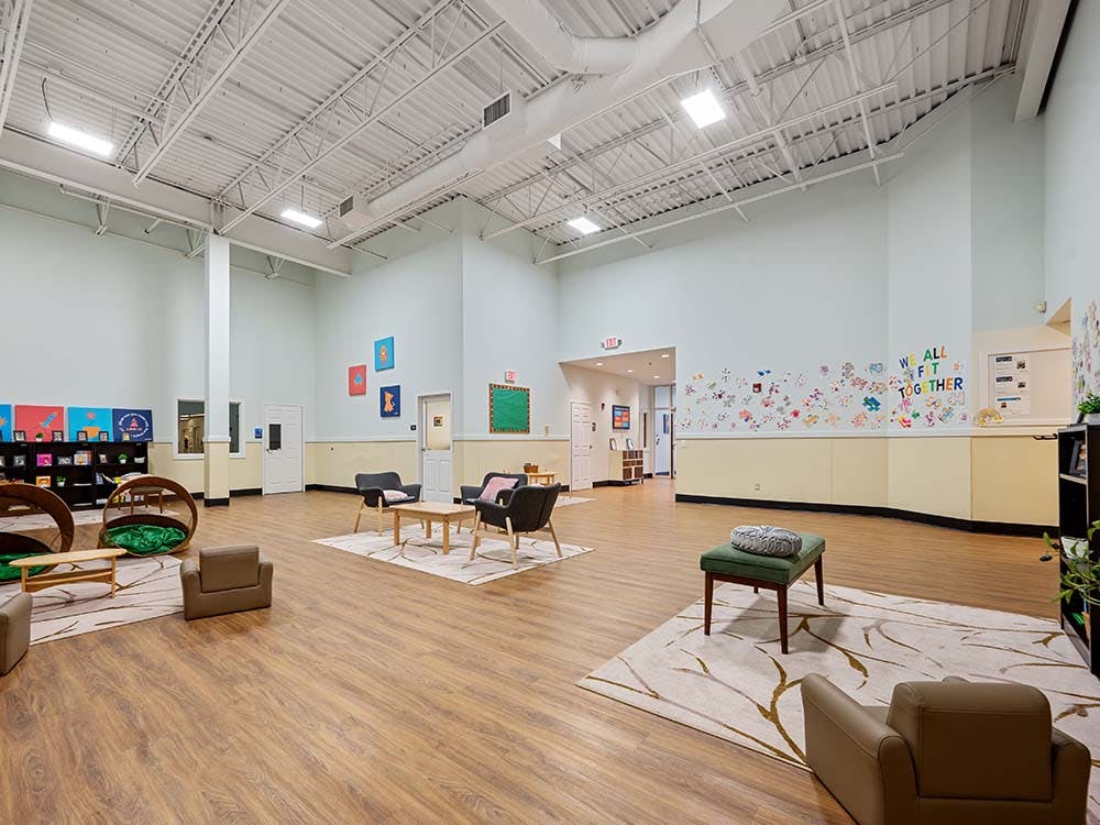 Large empty room with light blue walls, wood floor, and scattered seating areas