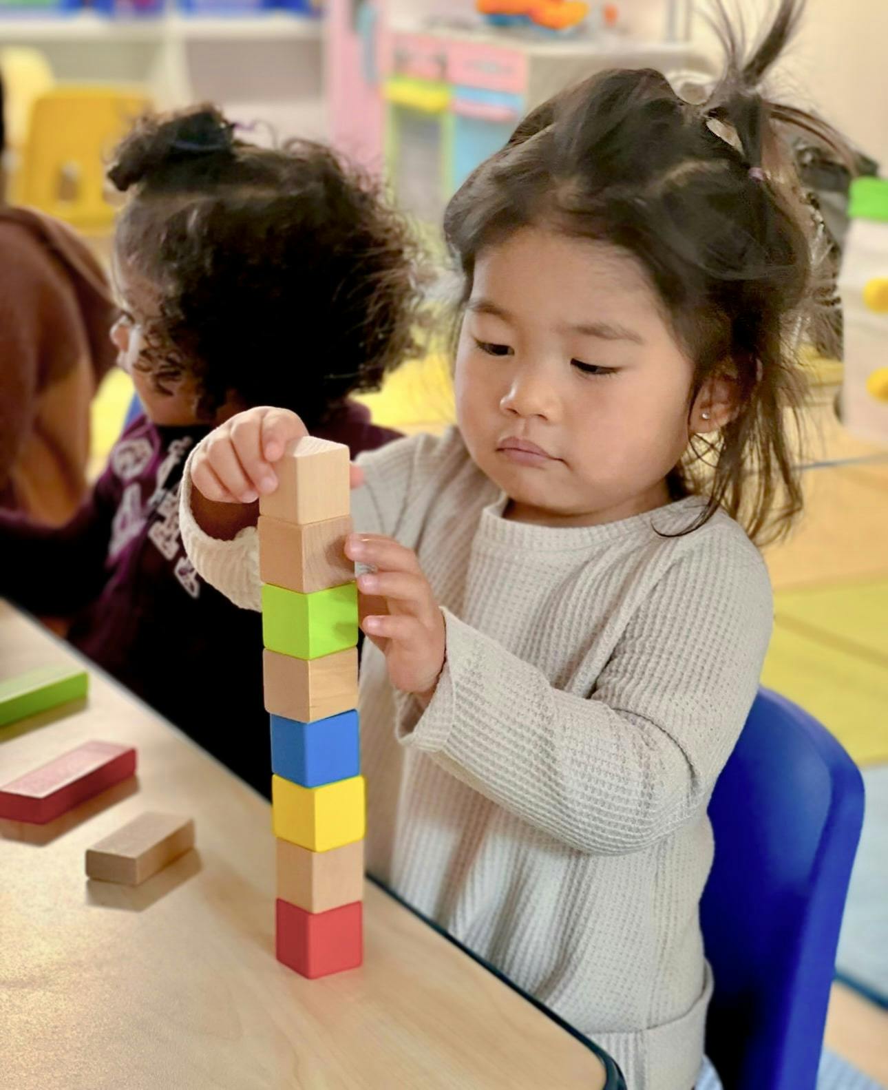 Child stacking colorful blocks on a table