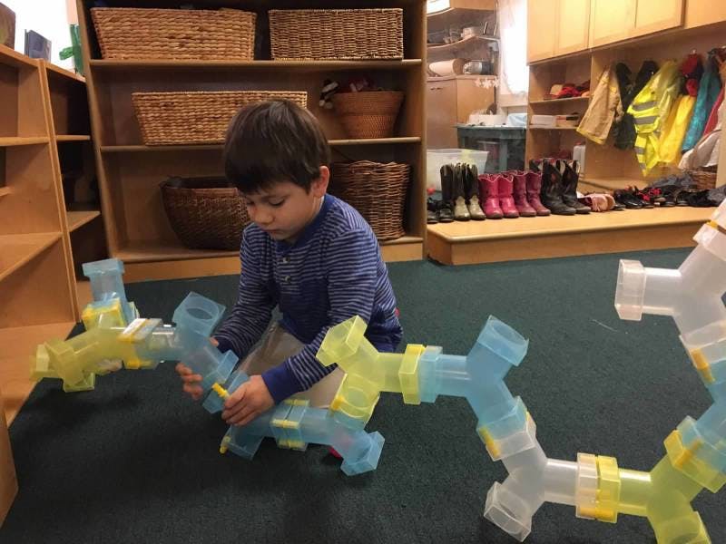 Child playing with building blocks on the floor in a classroom