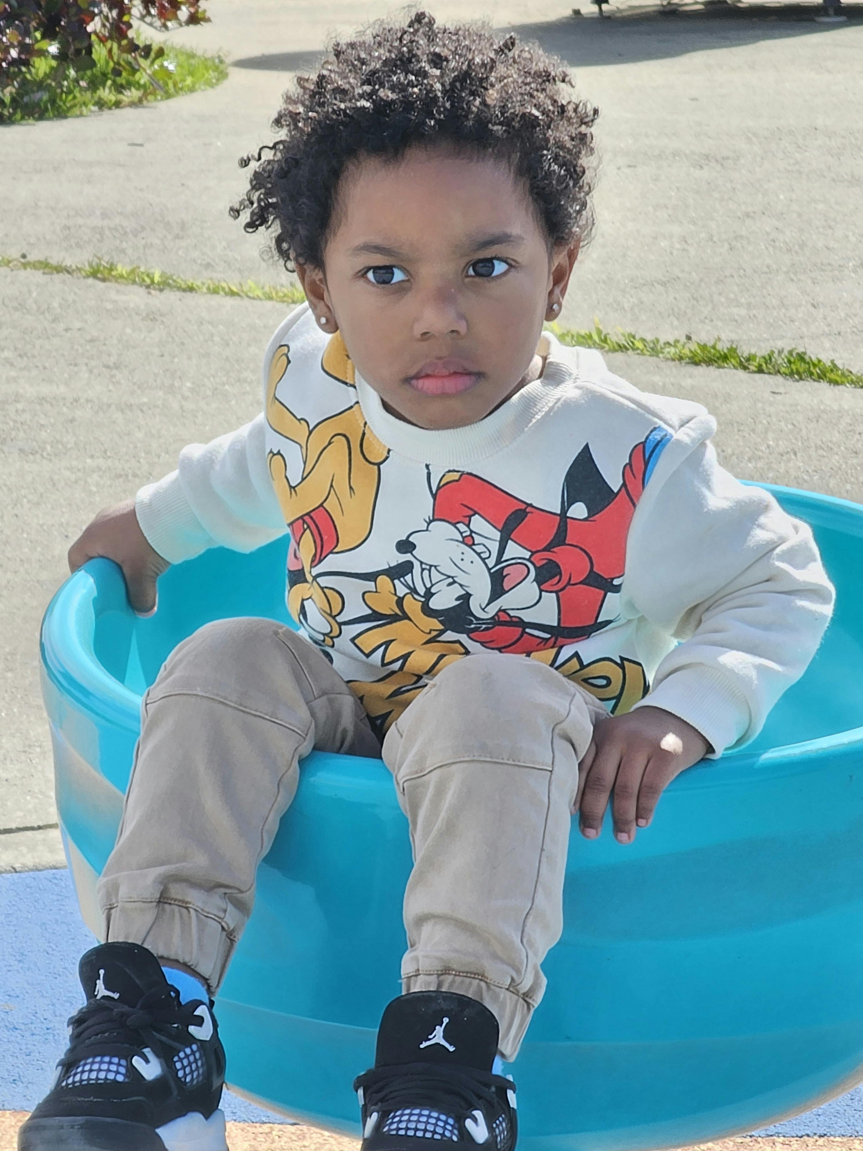 Child sitting in a blue plastic tub
