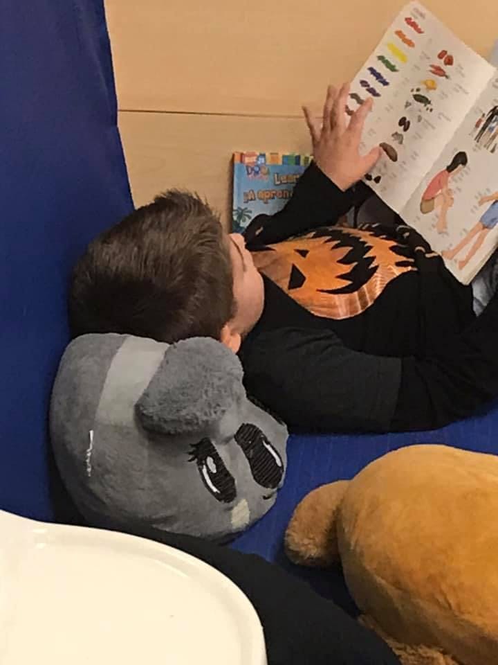 Child lying down reading a book