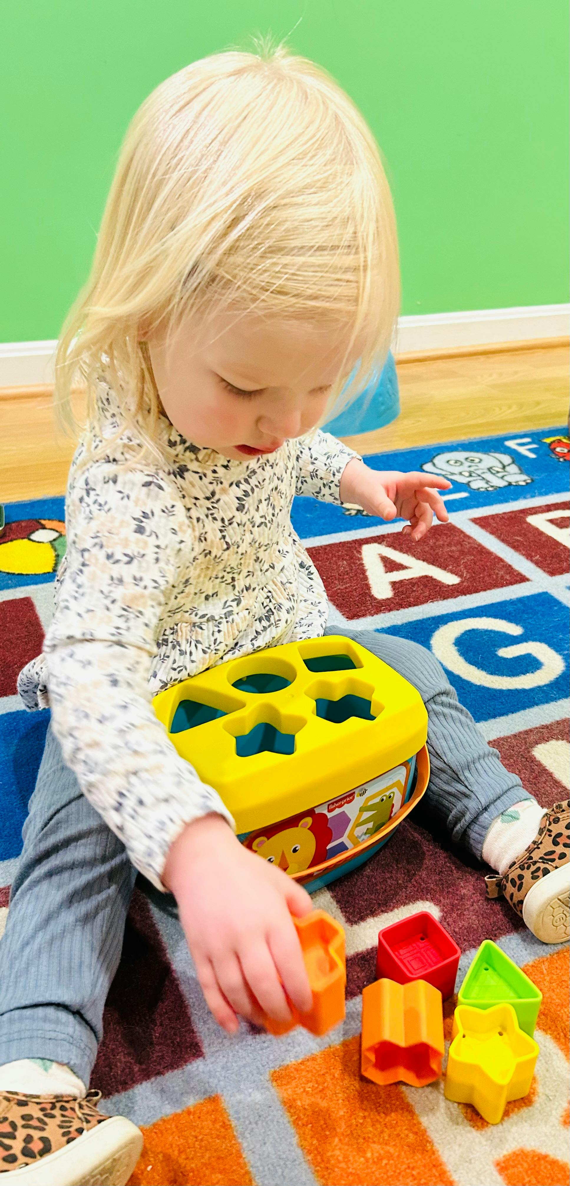 Child playing with a shape sorter toy on a rug