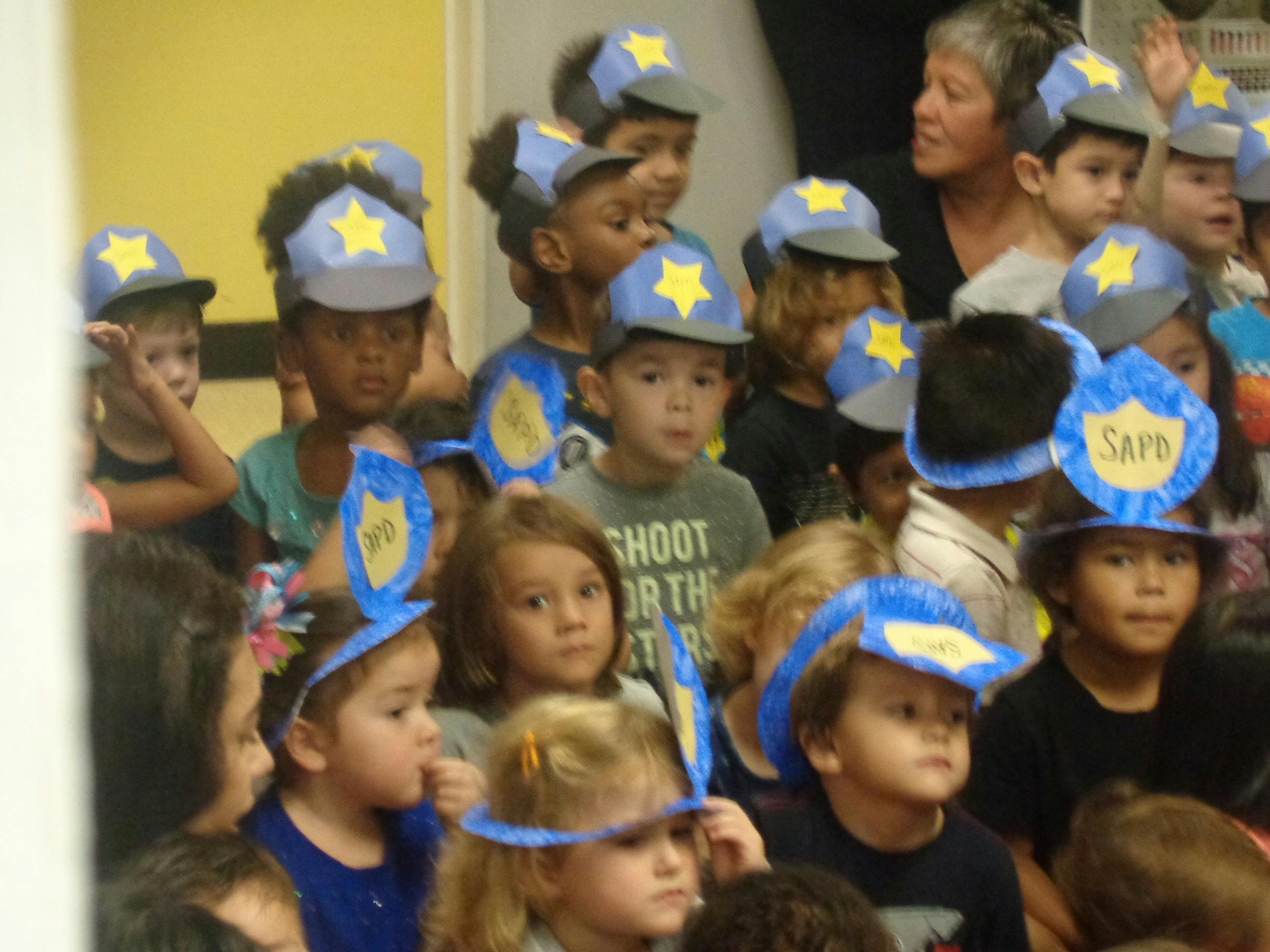 Group of children wearing blue hats with yellow stars and badges