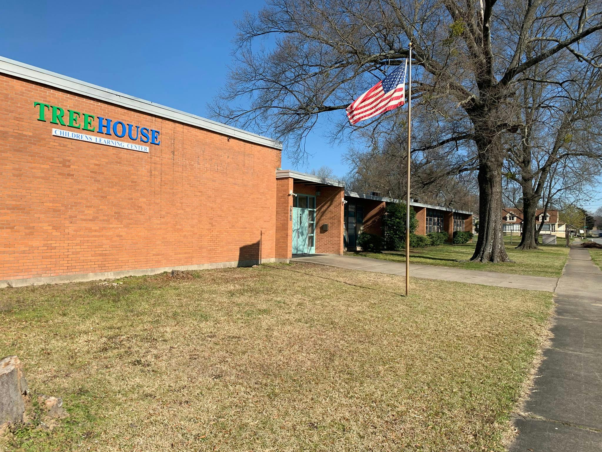 Brick building with "TREEHOUSE" sign and an American flag on a pole