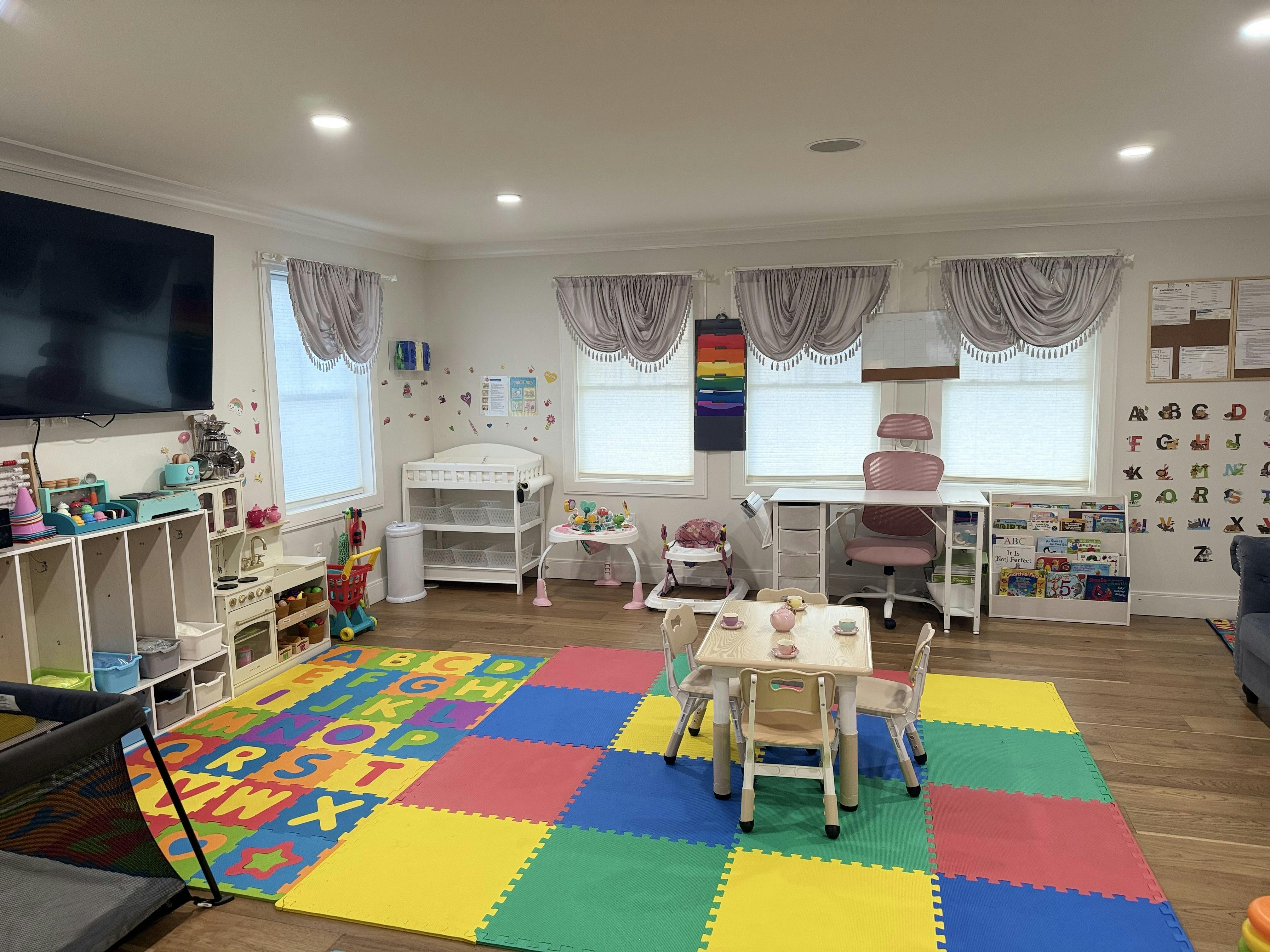 Child's play area with colorful alphabet mats, small table and chairs, and play kitchen