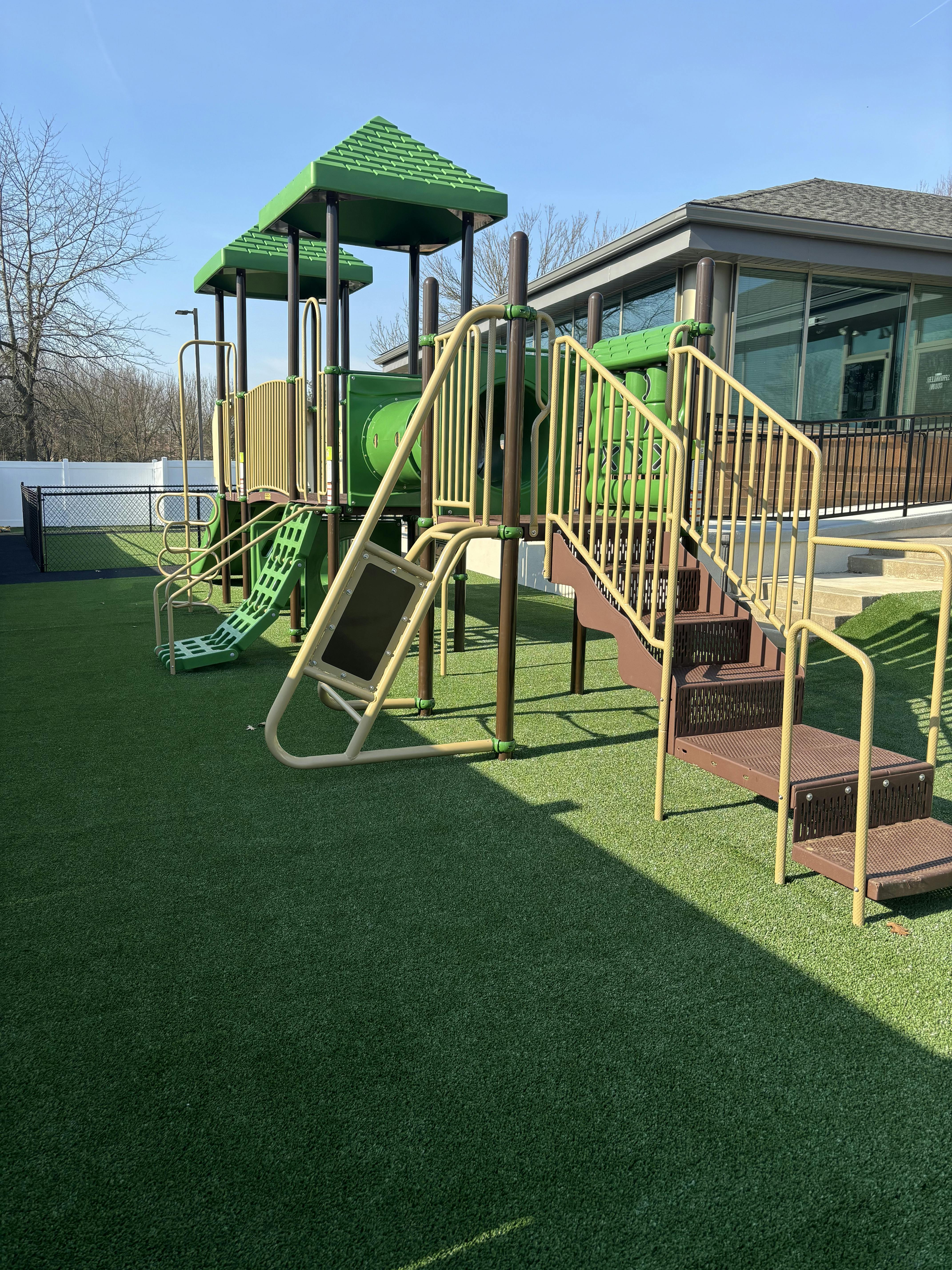 Playground with green turf and a building in the background