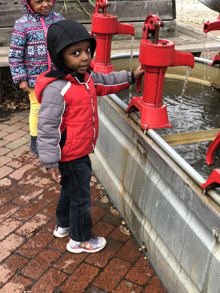 Child playing with a red water pump