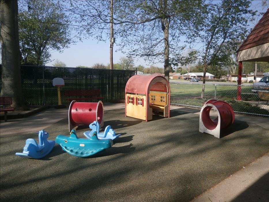 Playground area with red tunnels, a clubhouse, and blue spring riders