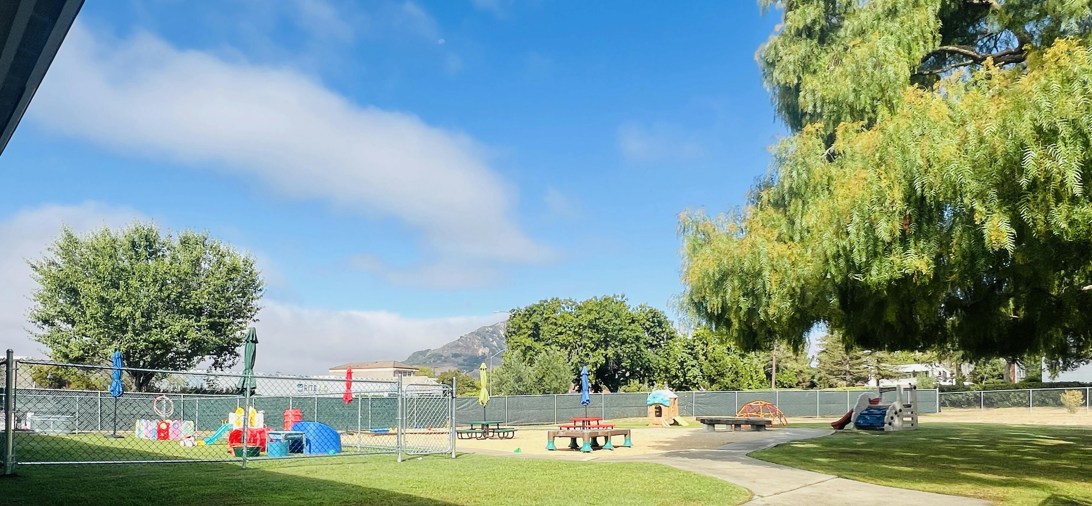 Outdoor playground with swings, slides, and benches under a blue sky