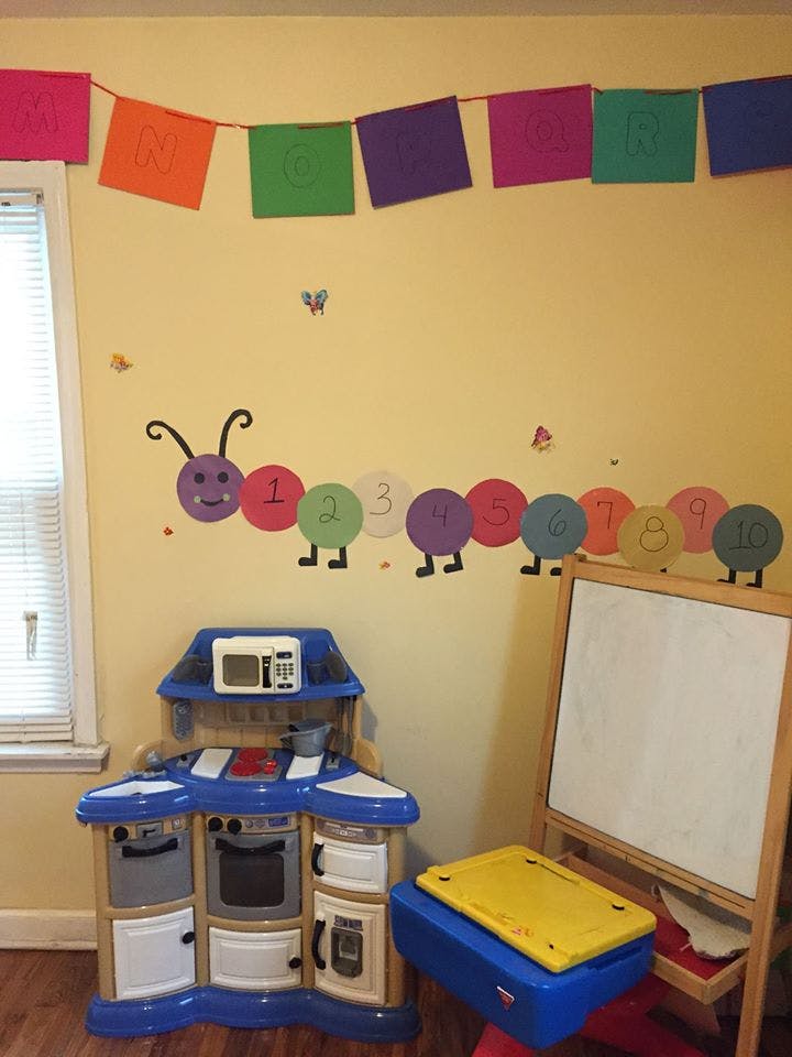 Play kitchen, easel, and caterpillar wall decor in a room
