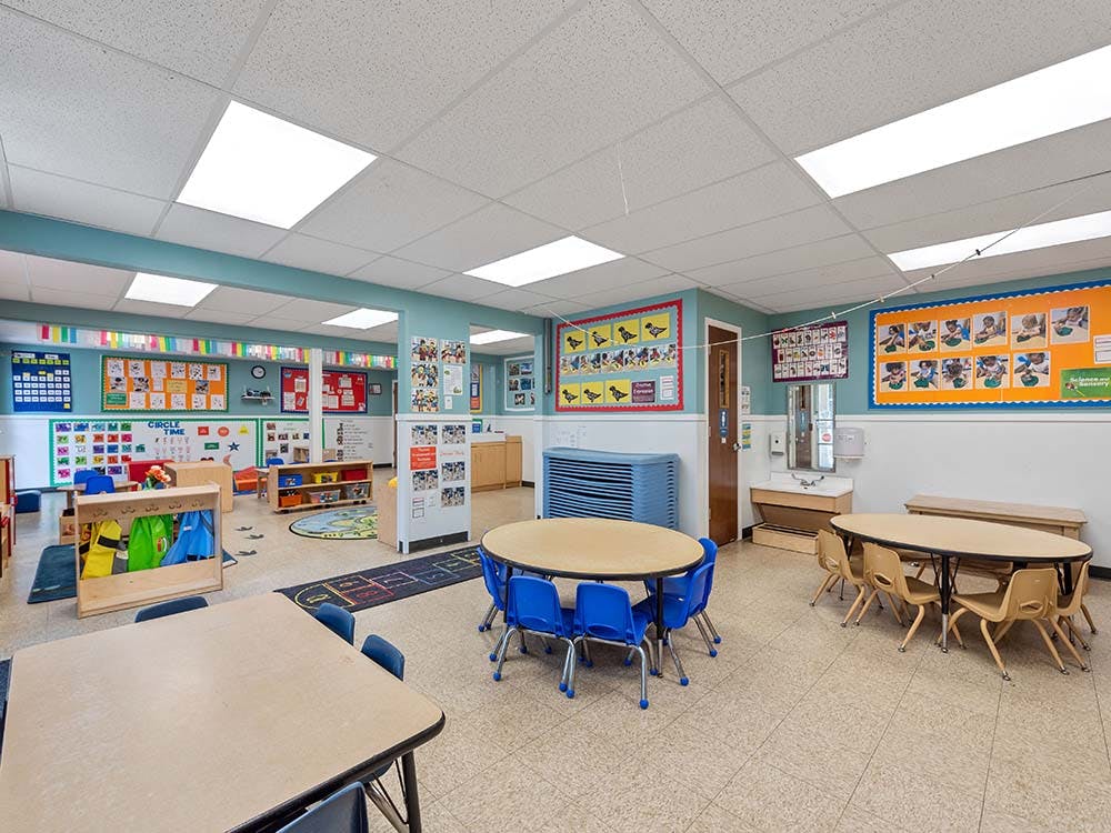Empty classroom with small tables and chairs, and colorful decorations on the walls