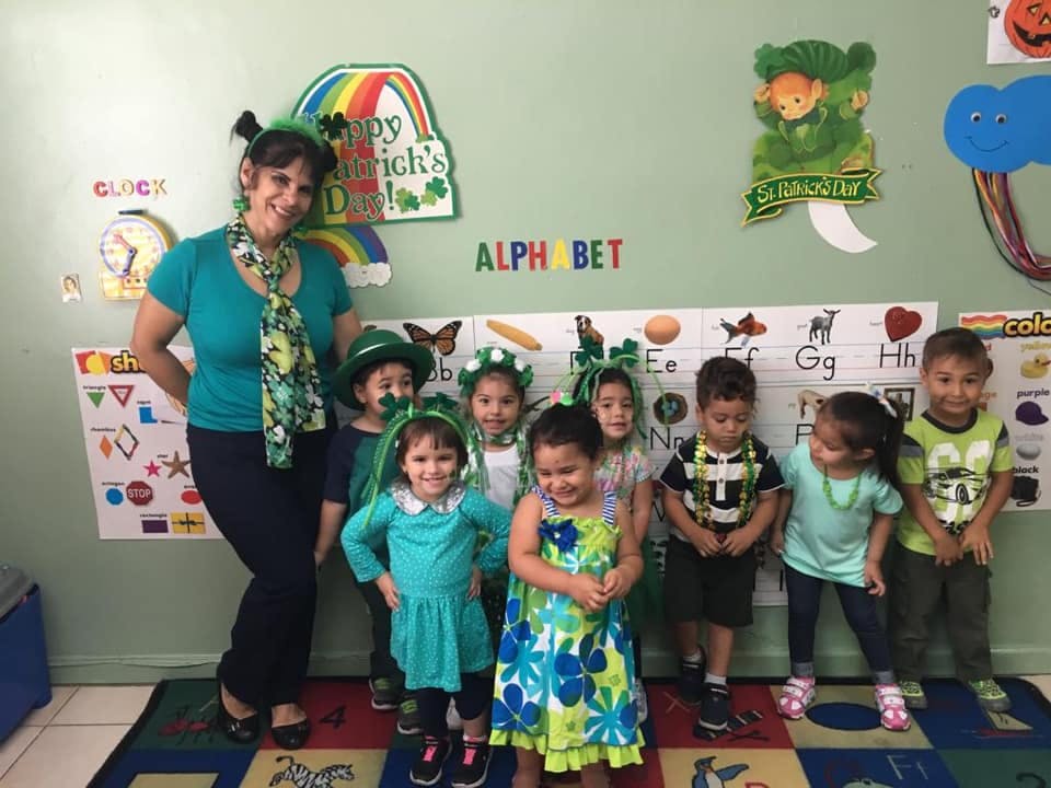 Adult and children in a classroom, some wearing green