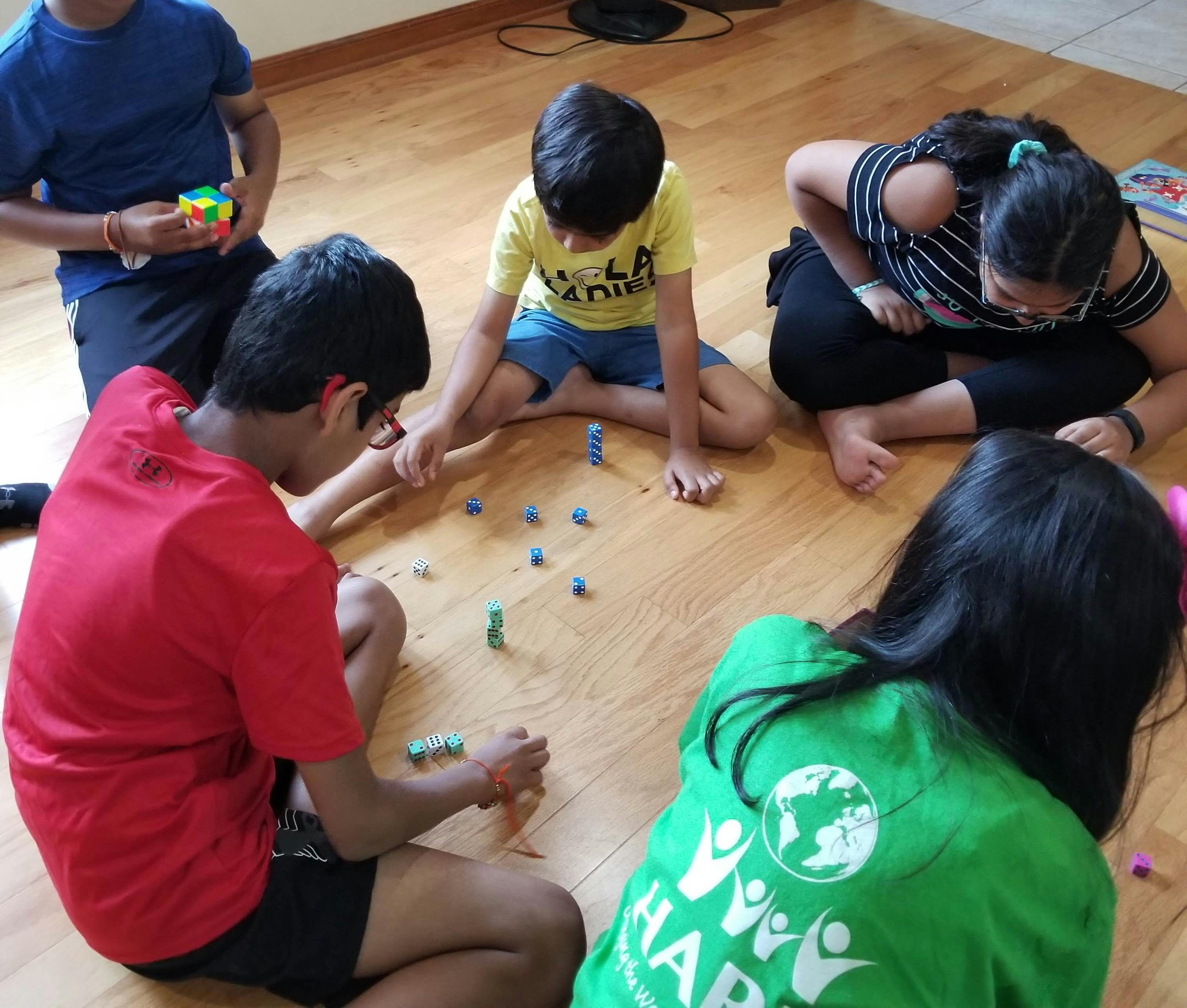 Group of children sitting on a wooden floor playing with dice
