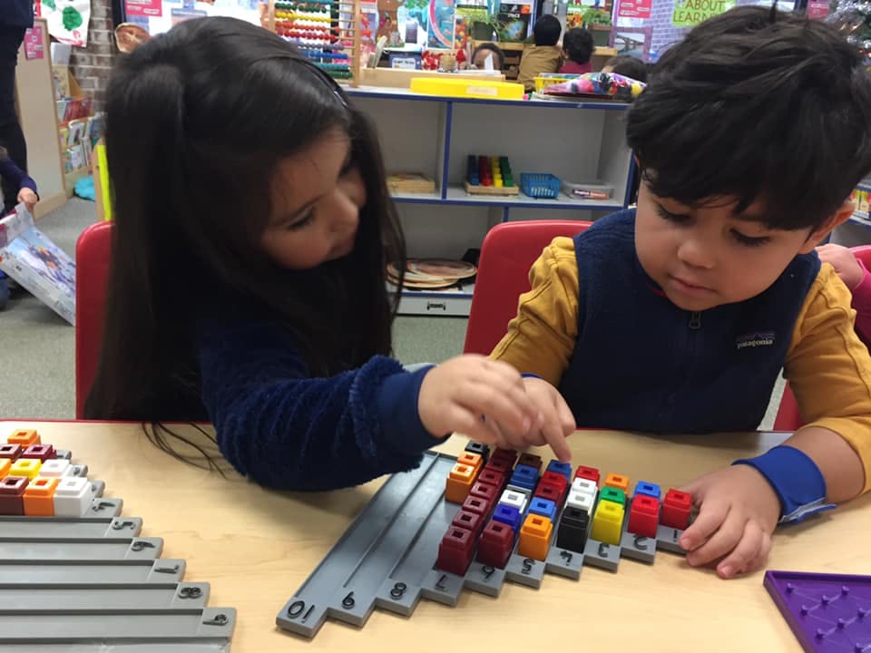 Two children playing with colorful building blocks on a table