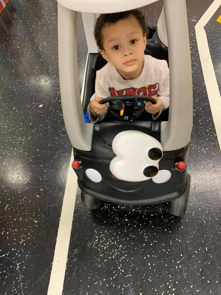 Child in a toy car holding the steering wheel