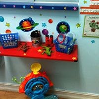 Toys and baskets on a red shelf with space-themed wall decorations