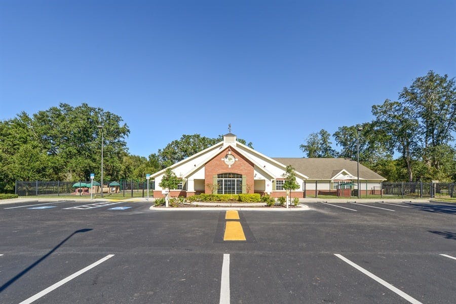Building with a brick facade and white siding, with a parking lot in front