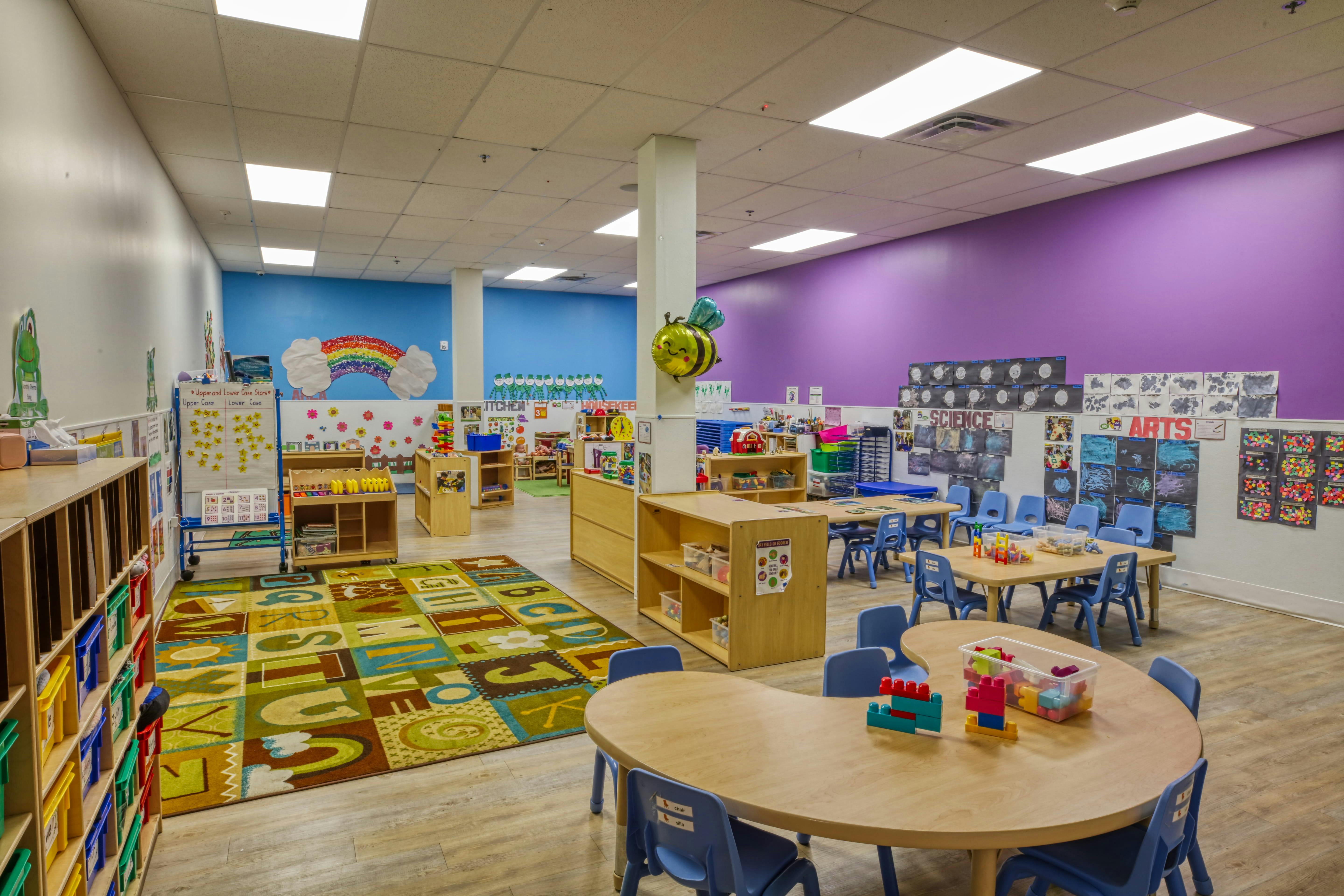 Classroom with colorful rug, small tables and chairs, and wall decorations