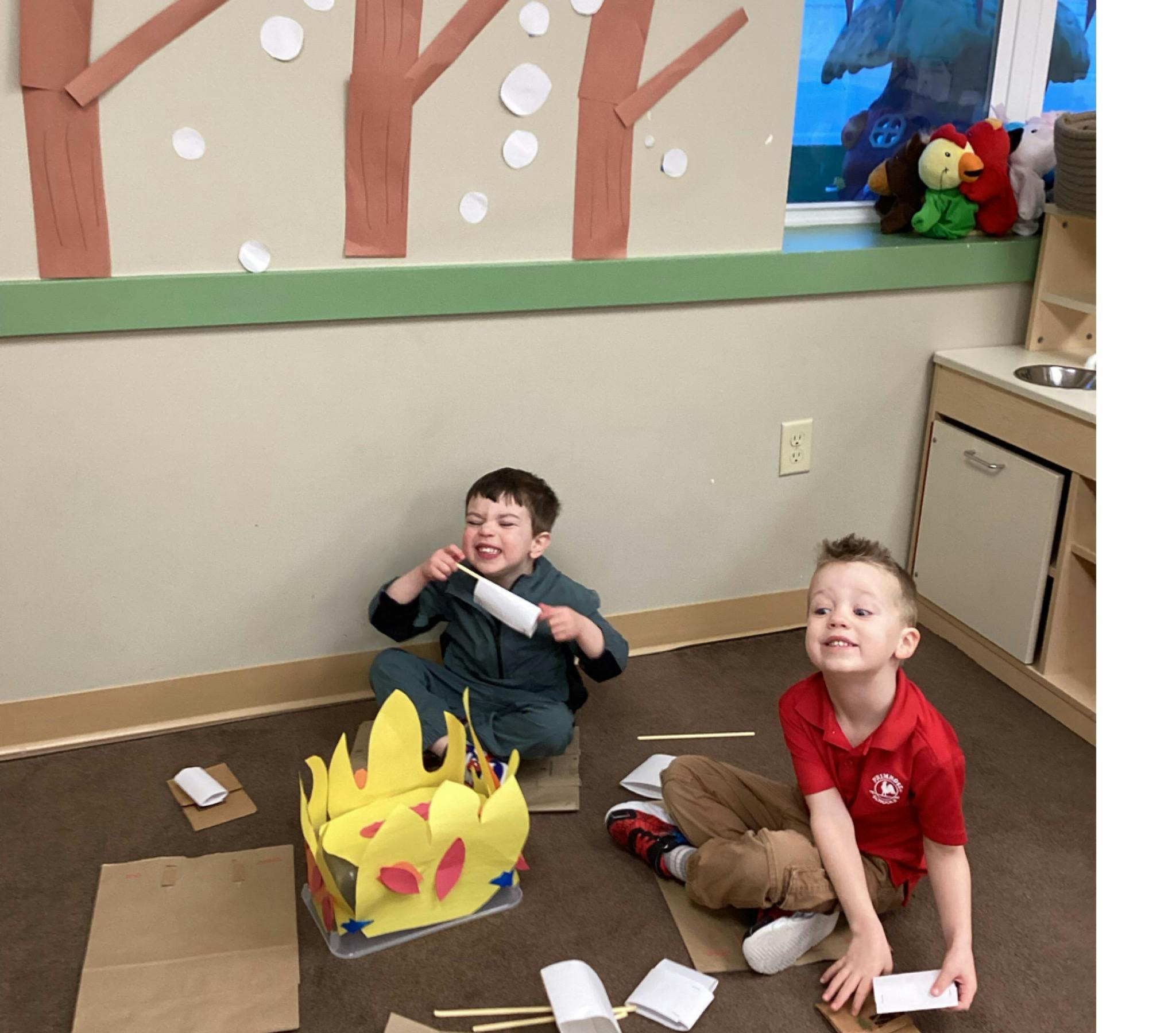 Two children sitting on the floor making crafts
