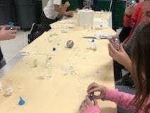 People working at a table with various small objects