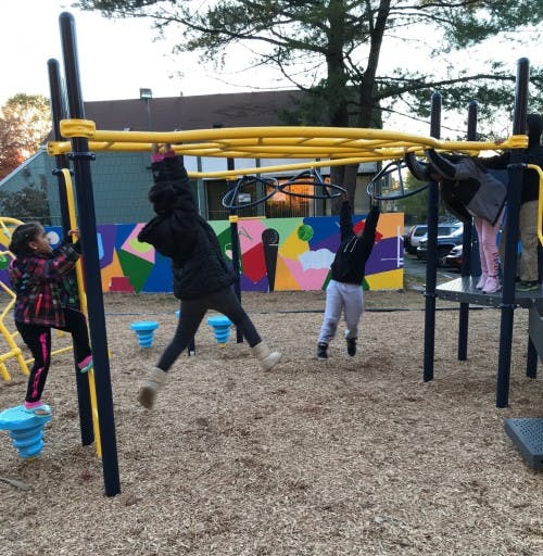 Children playing on monkey bars and playground equipment